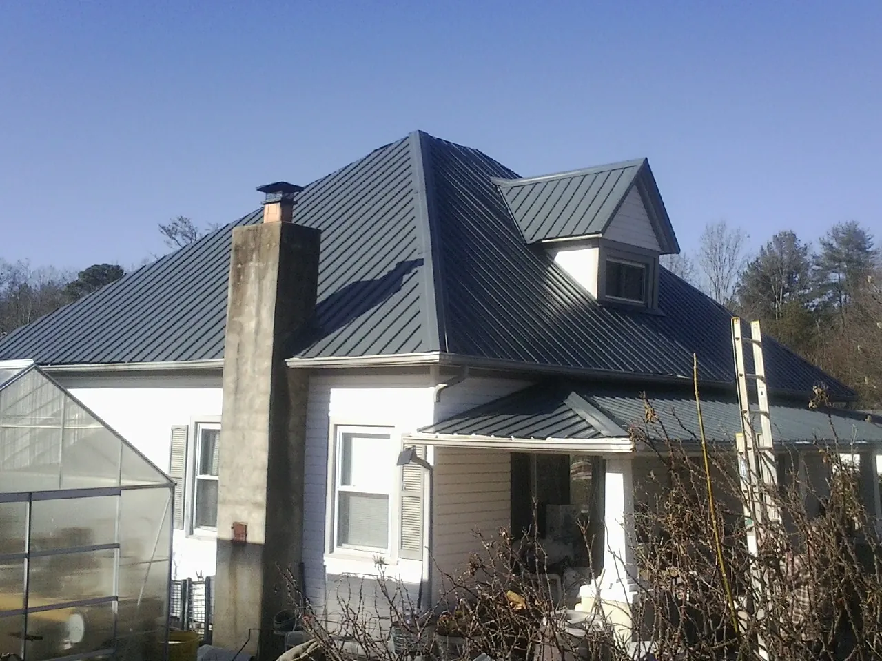 Dark blue standing seam metal roof on a white farmhouse with dormer — Slate & Tile Roof Repair by Roofing Brothers in Suffern