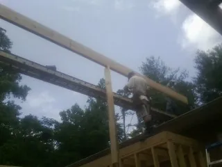 Carpenter setting a ridge beam over a new addition frame — Ice Dam Removal by Roofing Brothers in Suffern