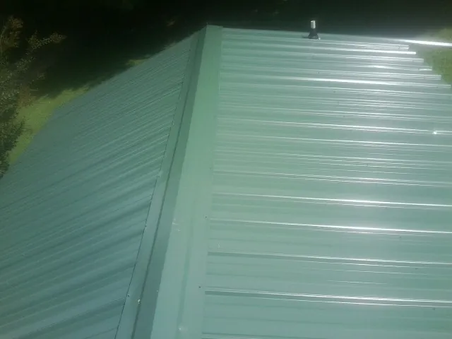 New green metal panels meeting at the ridge of a roof — Flat Roof Repair work by our crew in Suffern