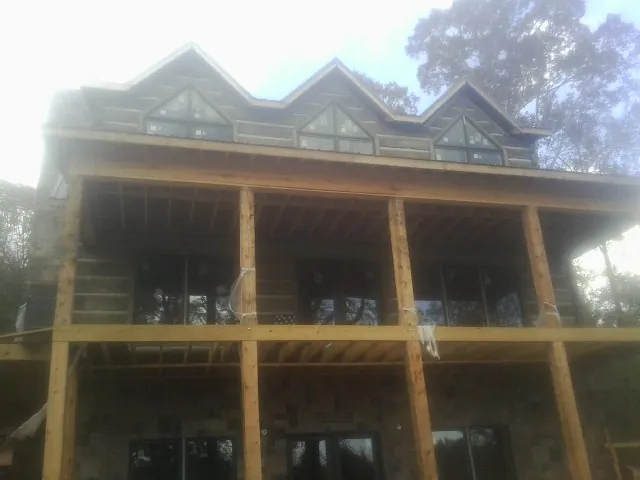 Dormers and porch framing on a large log home under construction — Roof Coating work by our crew in Suffern