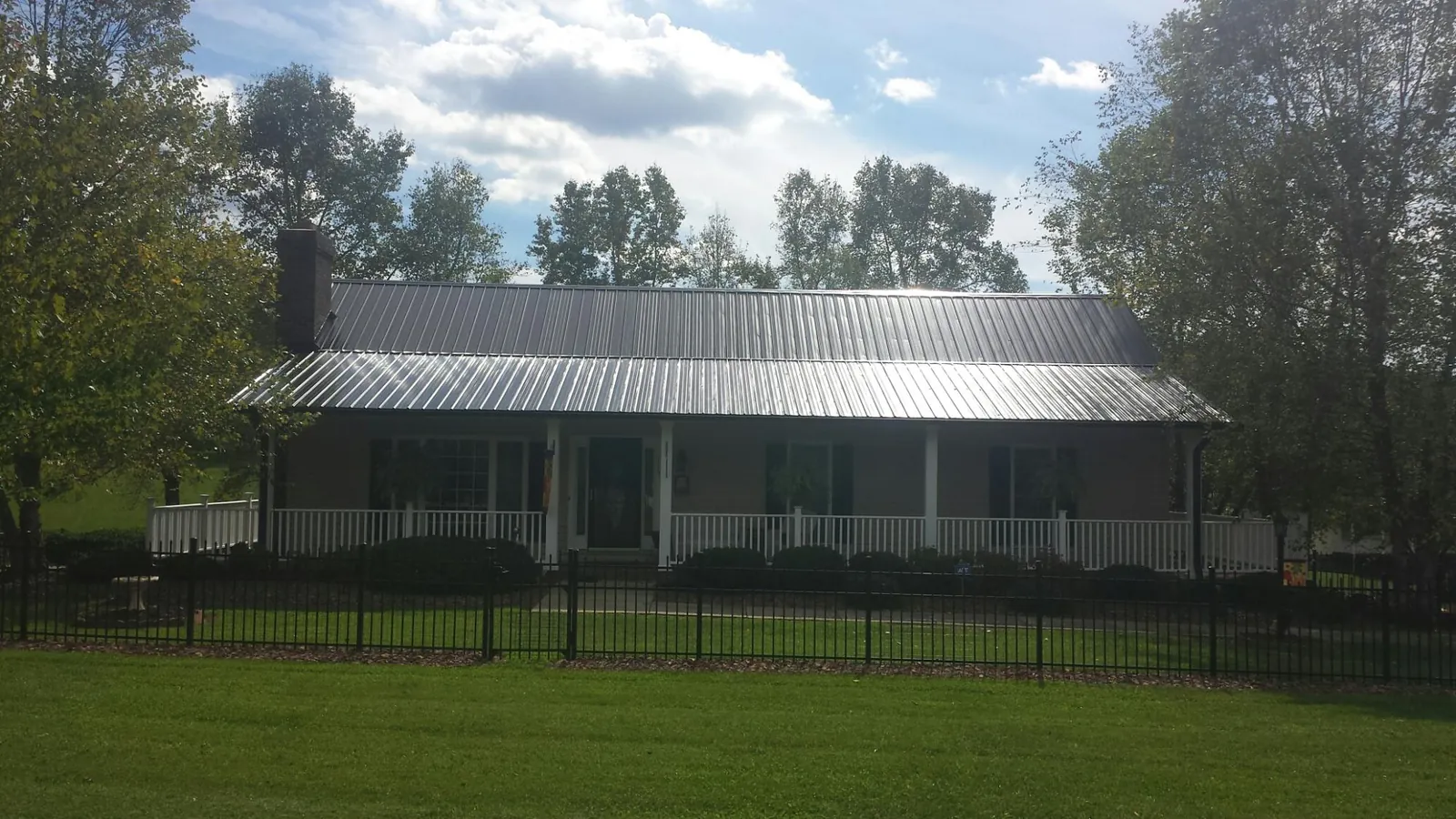 Gray metal roof on a brick ranch with a full width front porch — Gutter Guard Installation work by our crew in Suffern