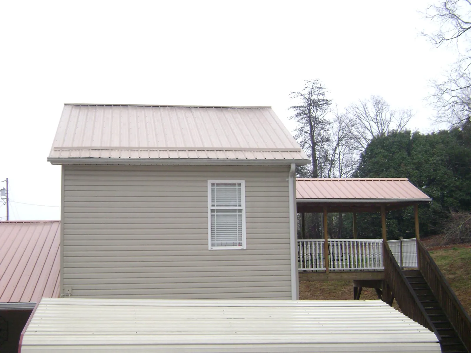 Tan metal roofs on a two story addition and attached porch, from a Roof Replacement job in Suffern