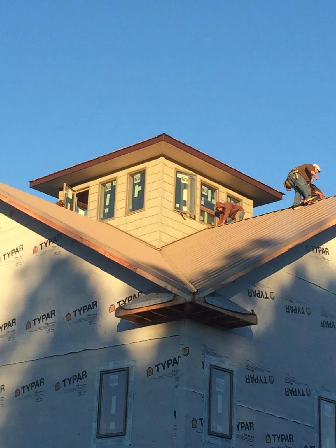 Roofers working around a rooftop cupola on a new metal roof at sunset — Roof Waterproofing in Suffern by Roofing Brothers